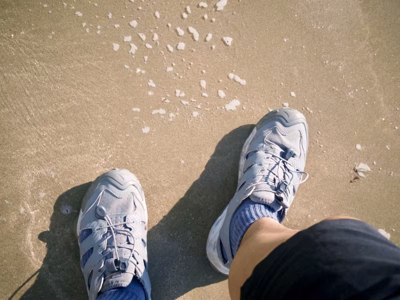 Wet shoes on sand with sea foam