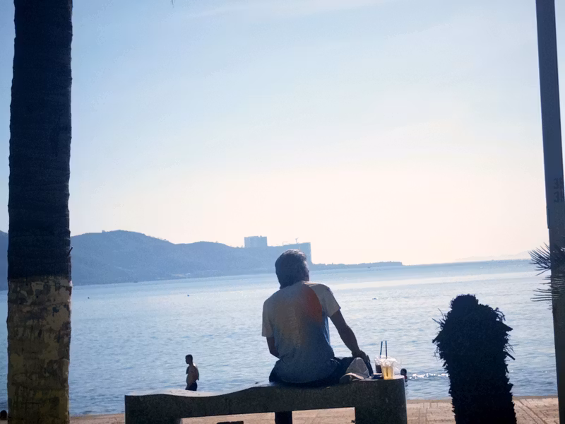 A person sitting on a bench looking out at Nha Trang Bay